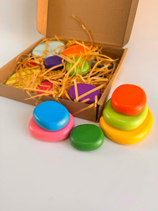 Coloured wooden pebbles in a box, showcasing vibrant hues for creative play and exploration.