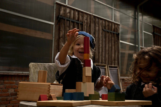 Children playing with colorful wooden building blocks, stacked creatively outdoors.