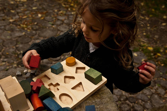 Child playing with a colorful Rainbow shape puzzle board, engaging in interactive learning with eco-friendly toys.