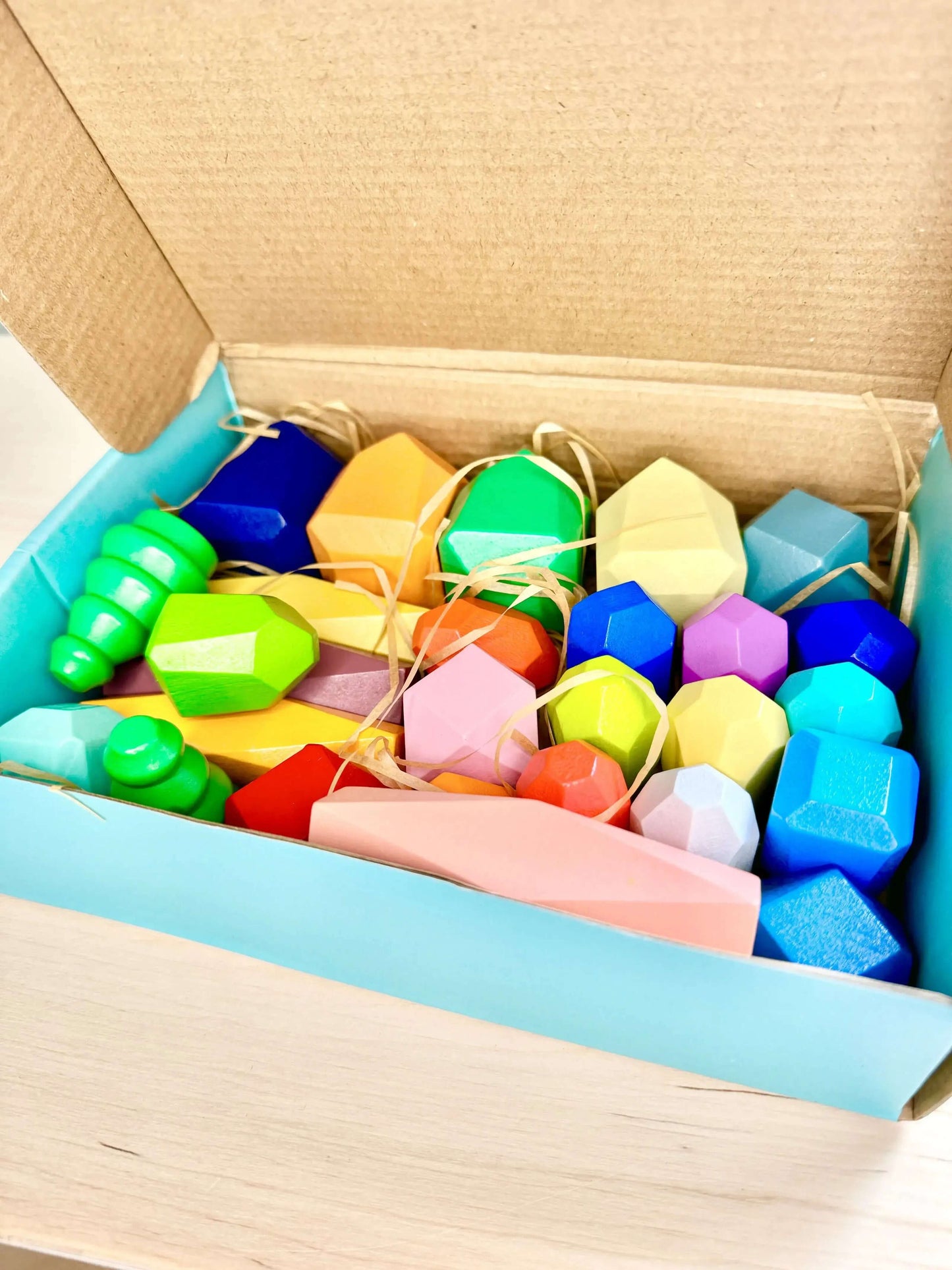 Wooden stacking and balancing rocks in a colorful box, perfect eco-friendly Montessori-inspired toy for open-ended play and learning.