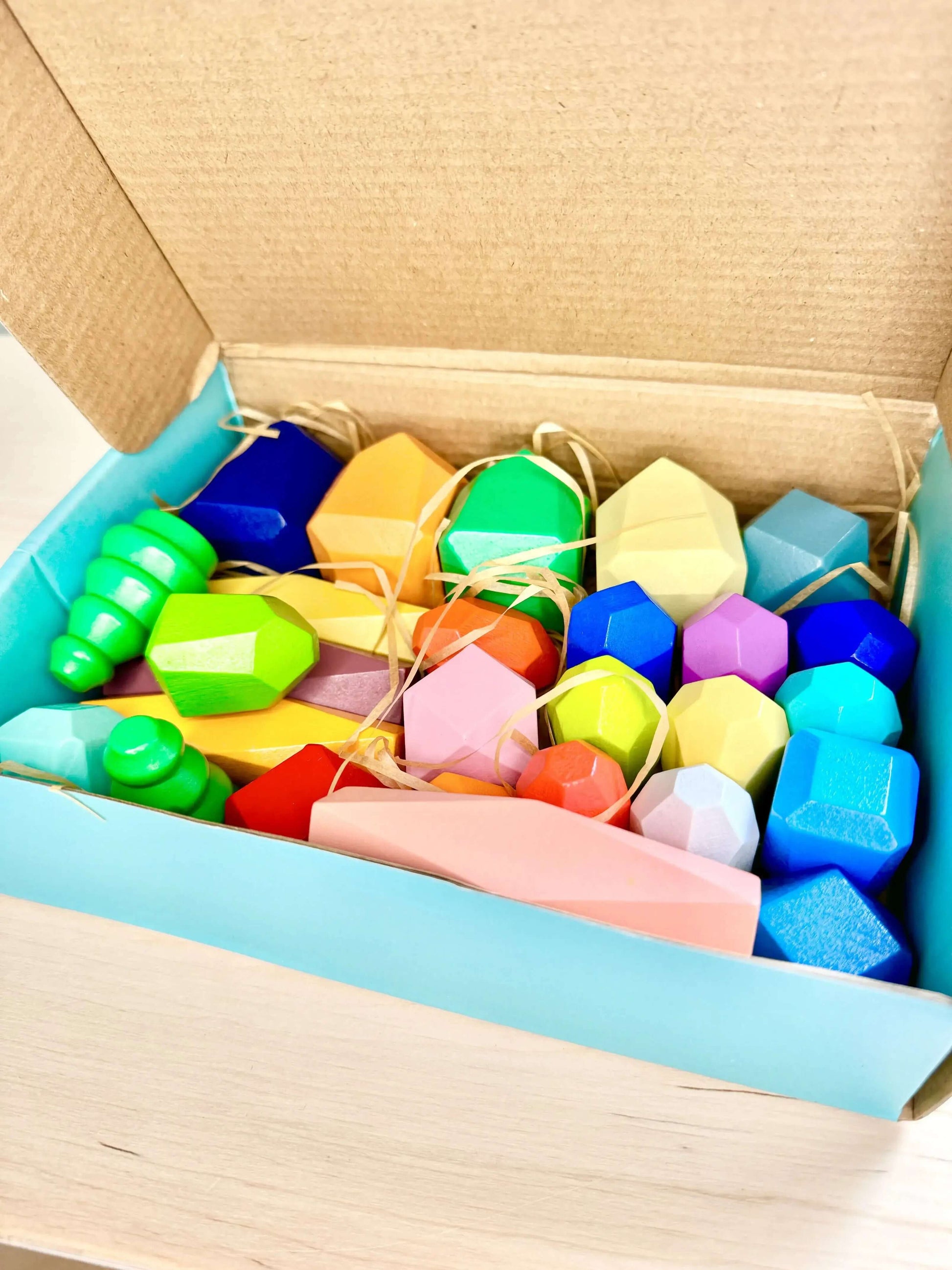 Wooden stacking and balancing rocks in a colorful box, perfect eco-friendly Montessori-inspired toy for open-ended play and learning.