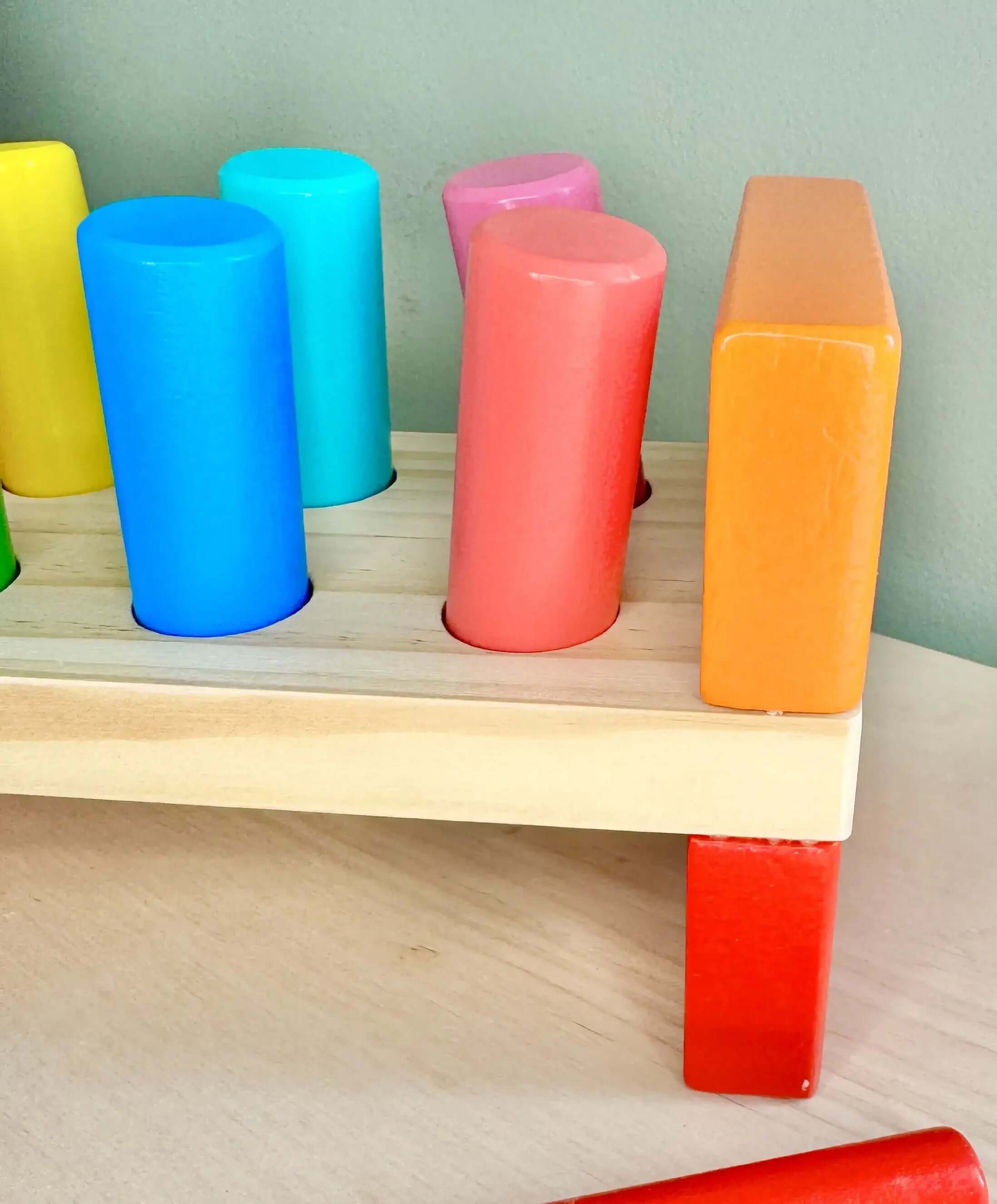 Vibrant wooden peg bench with colorful pegs, ideal for Montessori-inspired, open-ended play and enhancing fine motor skills.