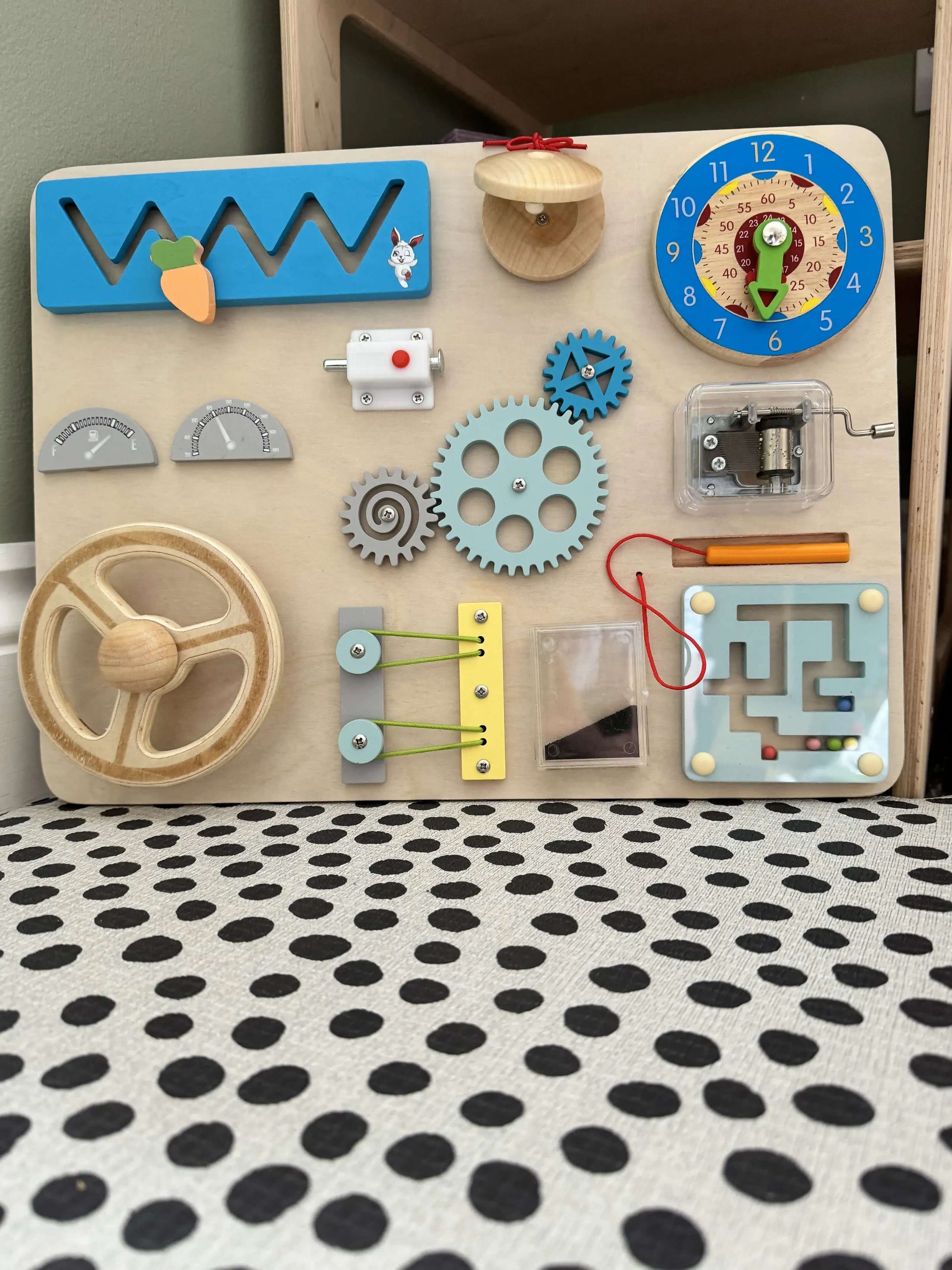 Car Steering Wheel Busy Board for toddlers featuring wooden Montessori-inspired elements like steering wheel, gears, clock, and music box.