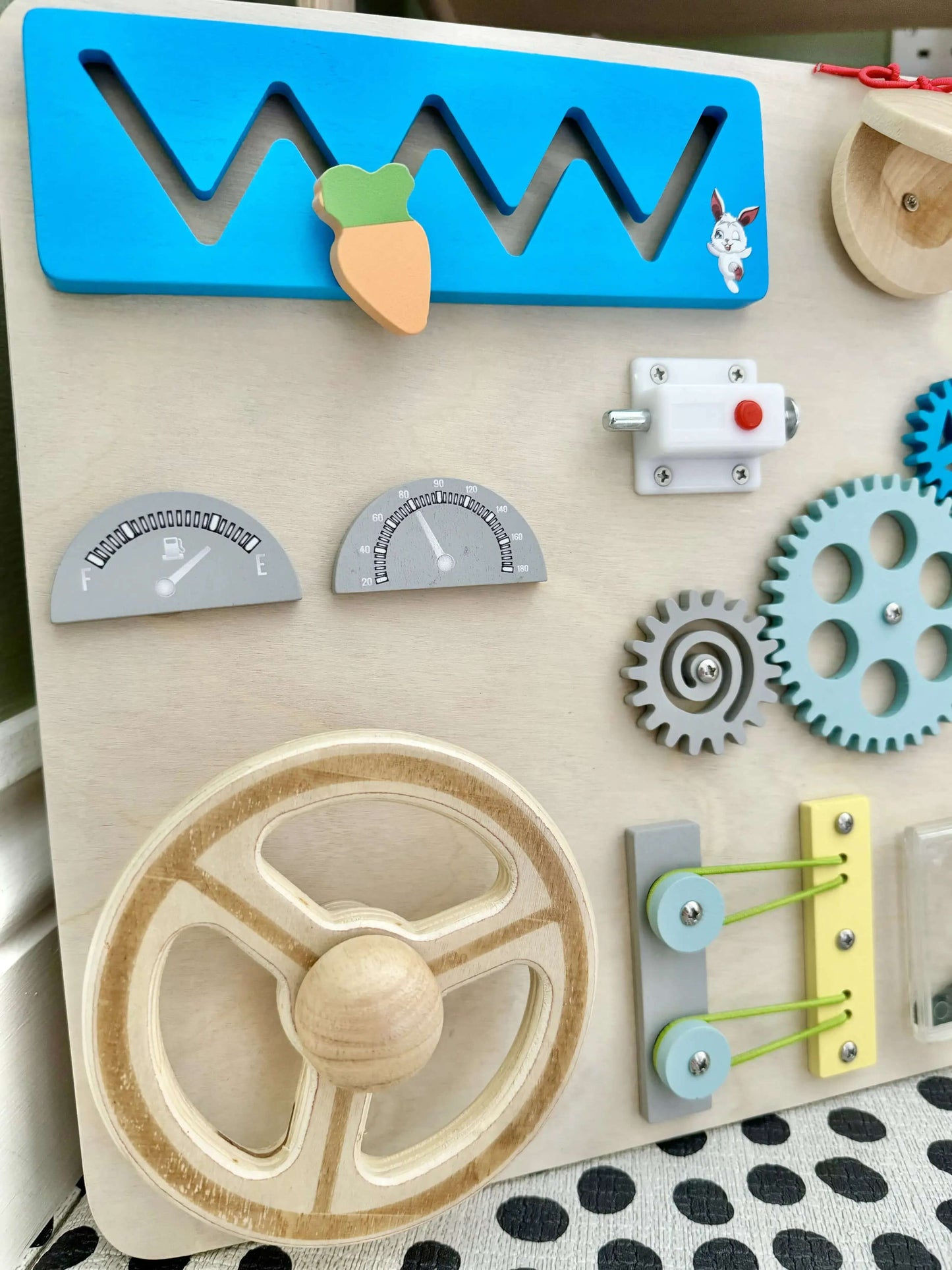 Montessori-inspired wooden busy board with steering wheel, gears, slider, and interactive elements for open-ended play and eco-friendly fun.