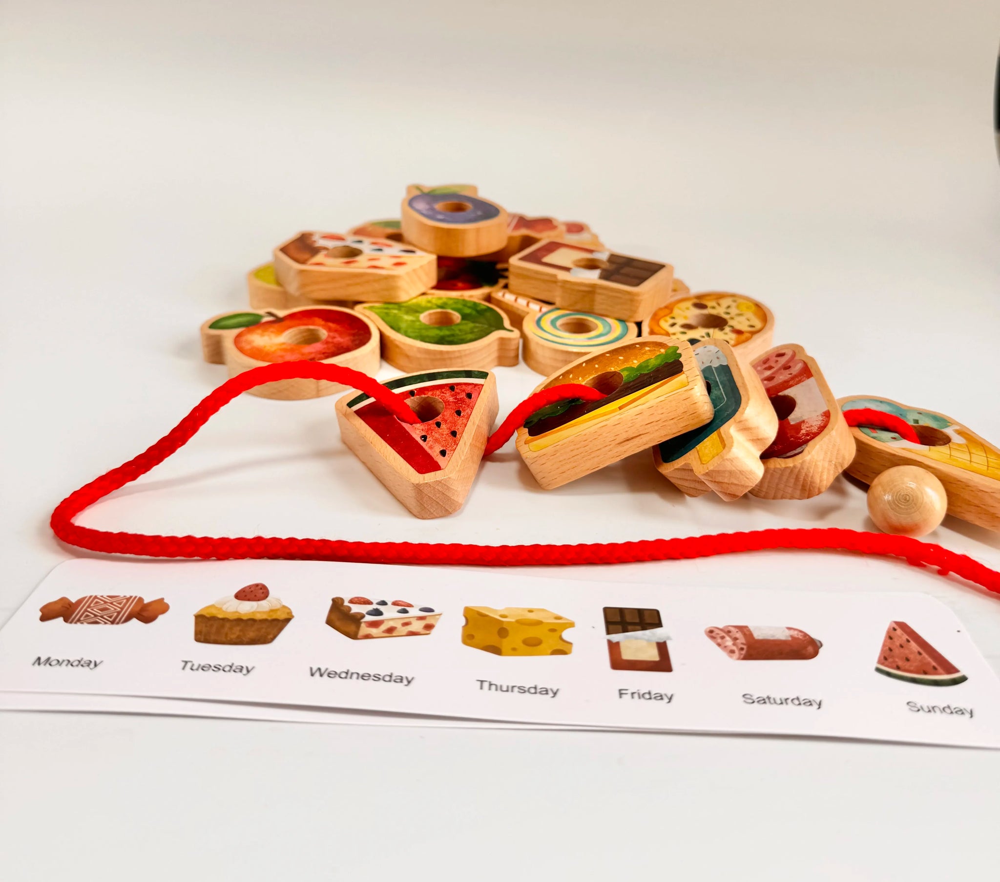 Colorful wooden food pieces and caterpillar toy with themed menu cards for imaginative play and learning.