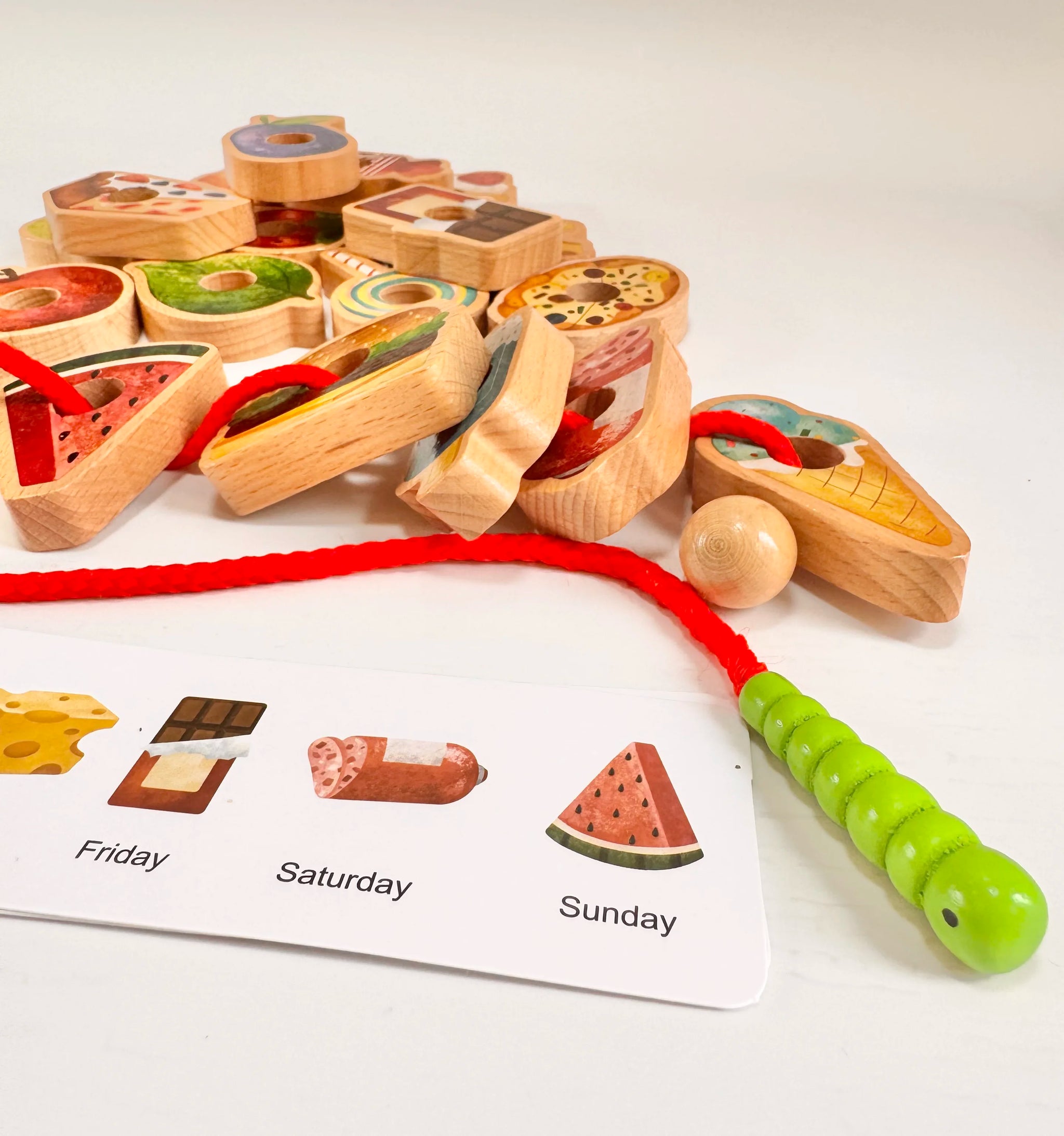Colorful wooden food pieces and caterpillar threading toy with menu cards for kids' imaginative play.