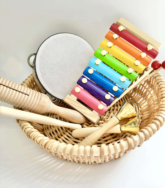 Colorful wooden musical instruments in a wicker basket for Montessori inspired open-ended play and sensory development.