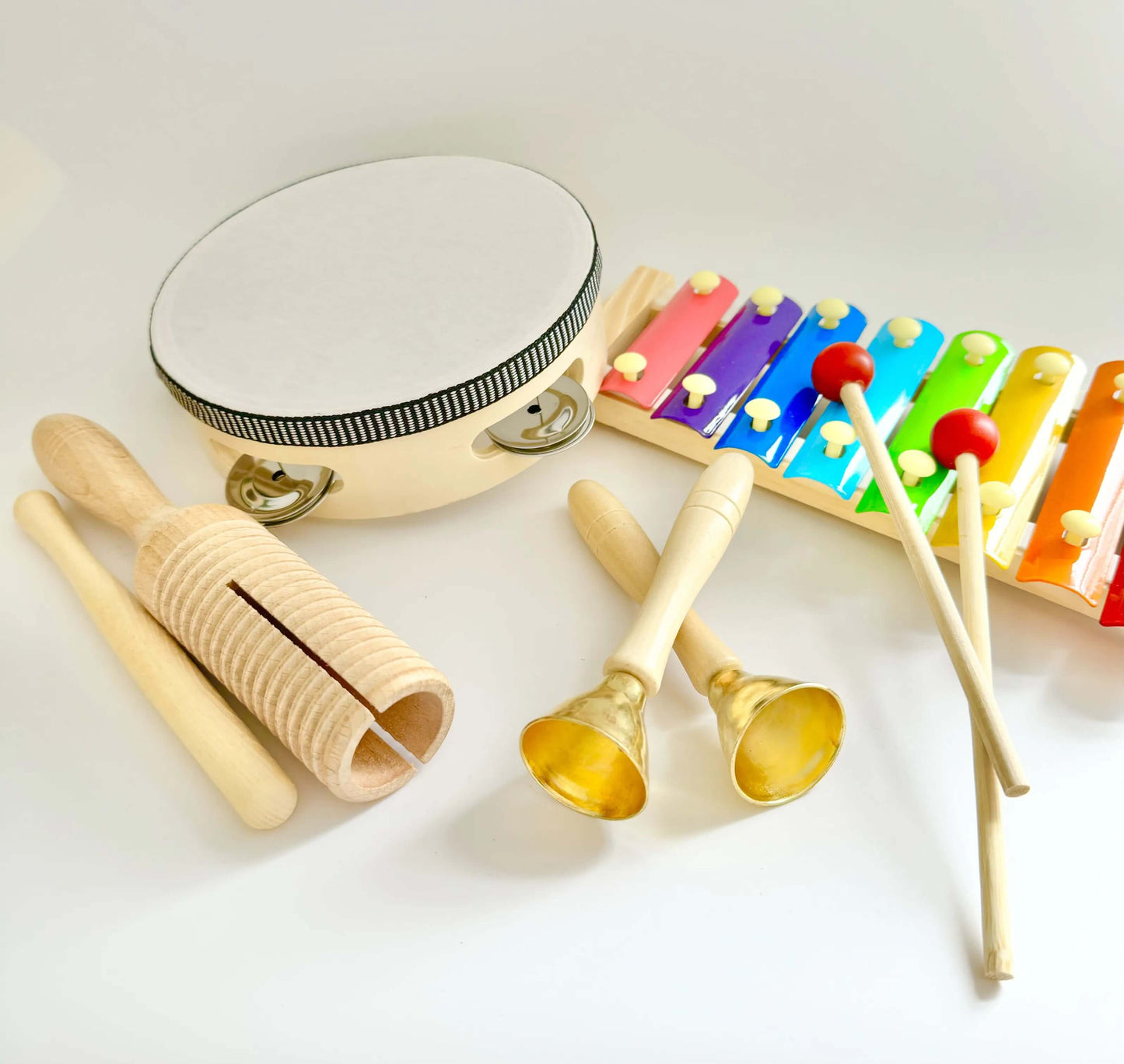 Montessori inspired wooden toy musical instruments for open-ended play including tambourine, xylophone, and bells. Eco-friendly toy set.