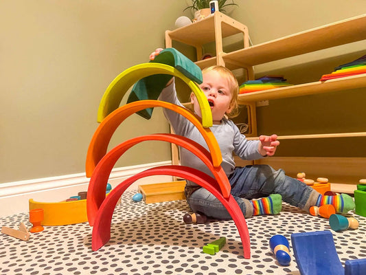 A child playing with a wooden rainbow stacker