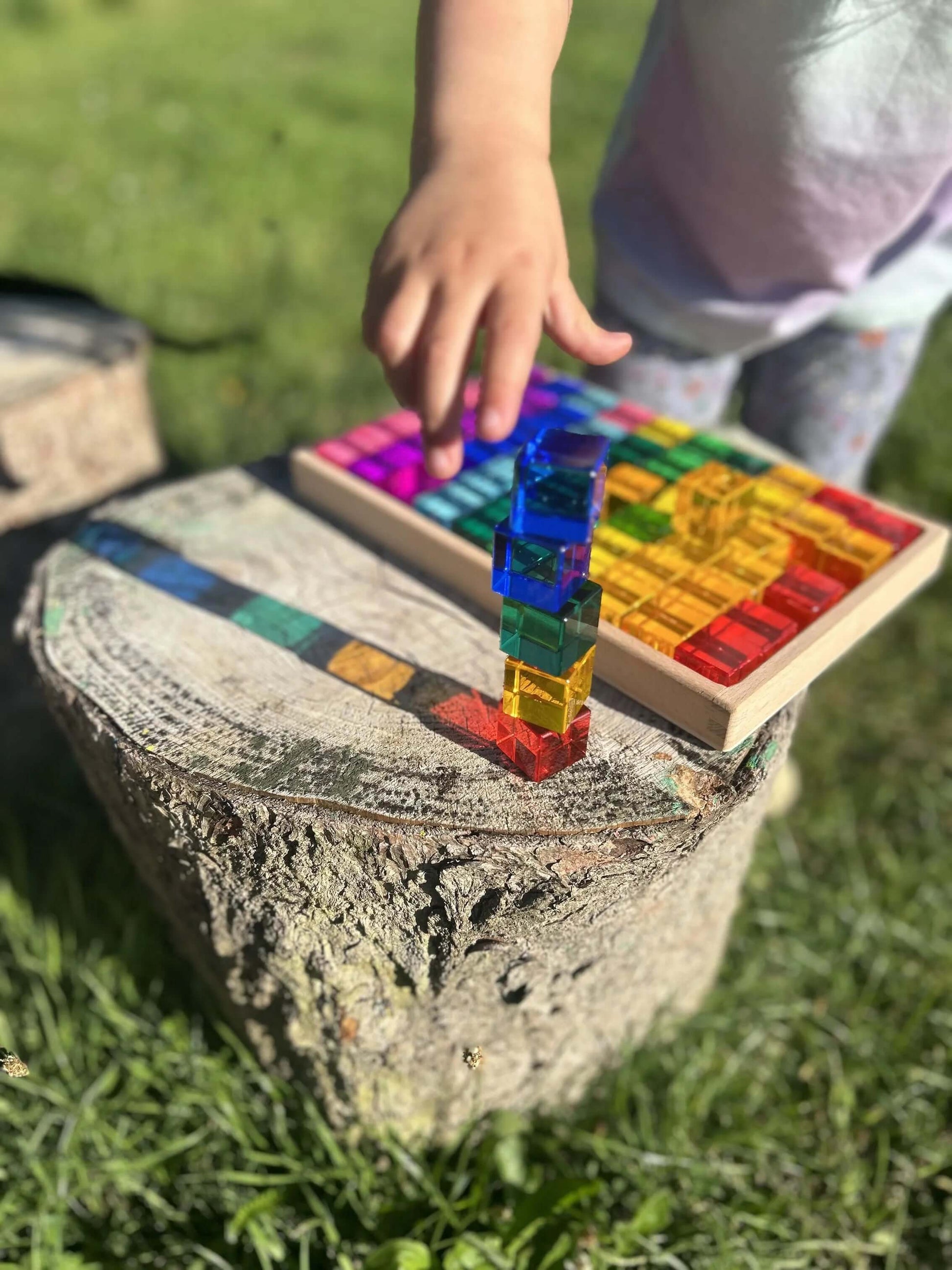 Child playing with Permeability Cubes wooden Montessori toy set outdoors, showcasing colorful open-ended, eco-friendly play.