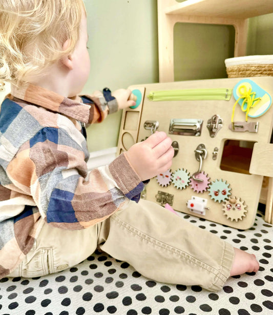 Child playing with Montessori inspired wooden toy Busy Board featuring gears, latches, and eco-friendly components for open-ended play.