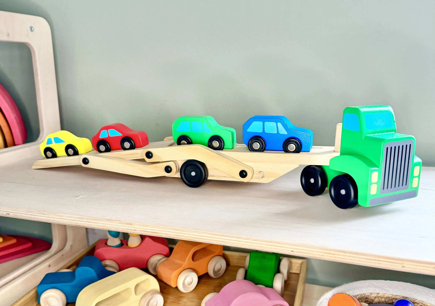 Wooden toy car carrier with colorful cars on a shelf, ideal for Montessori-inspired open-ended play and eco-friendly fun.