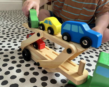 Child playing with wooden toy car carrier featuring colorful cars on a polka dot mat, promoting Montessori-inspired, open-ended play and eco-friendly fun