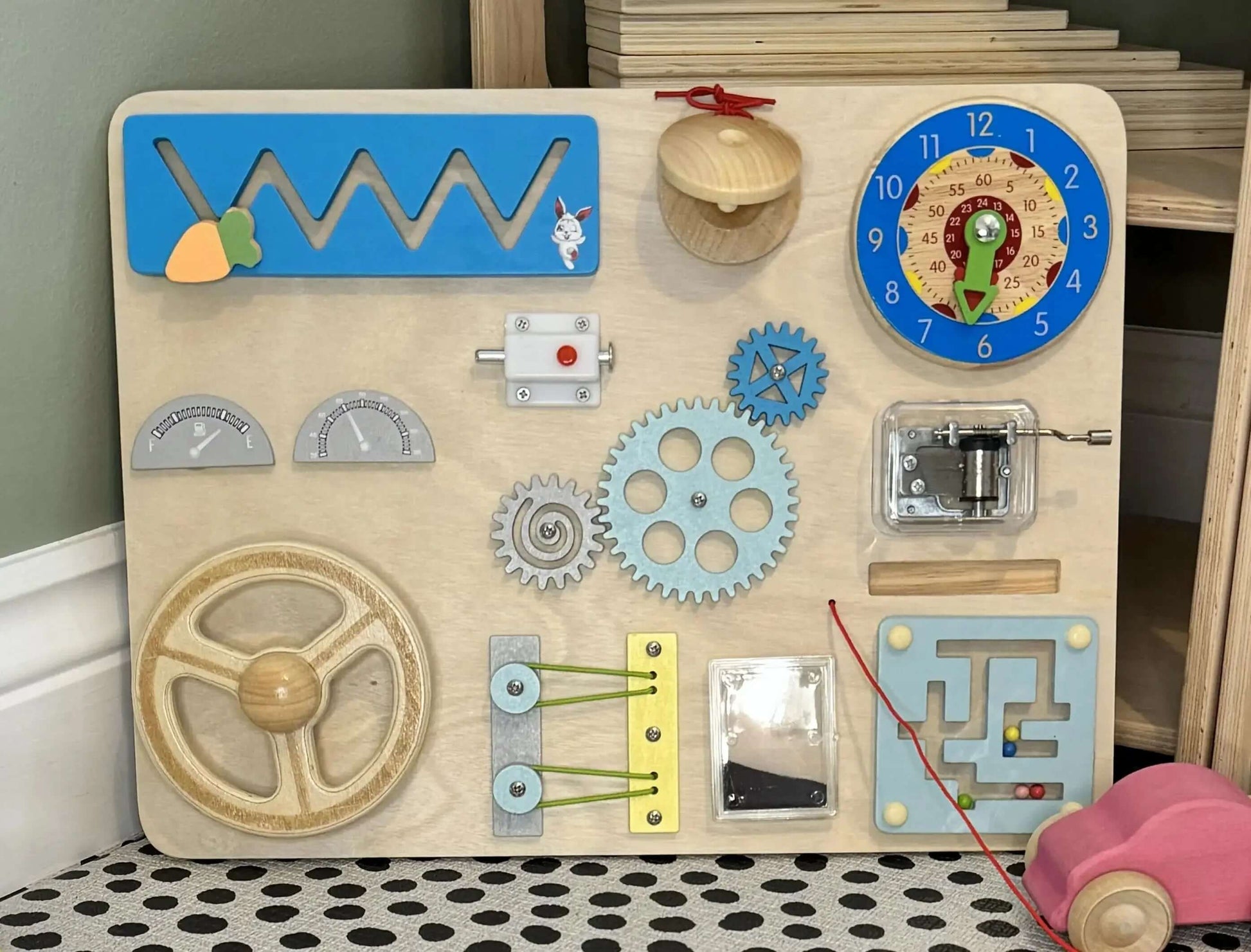 Wooden Montessori inspired busy board with steering wheel, gears, clock, slider, musical instrument, and eco-friendly design for open-ended play