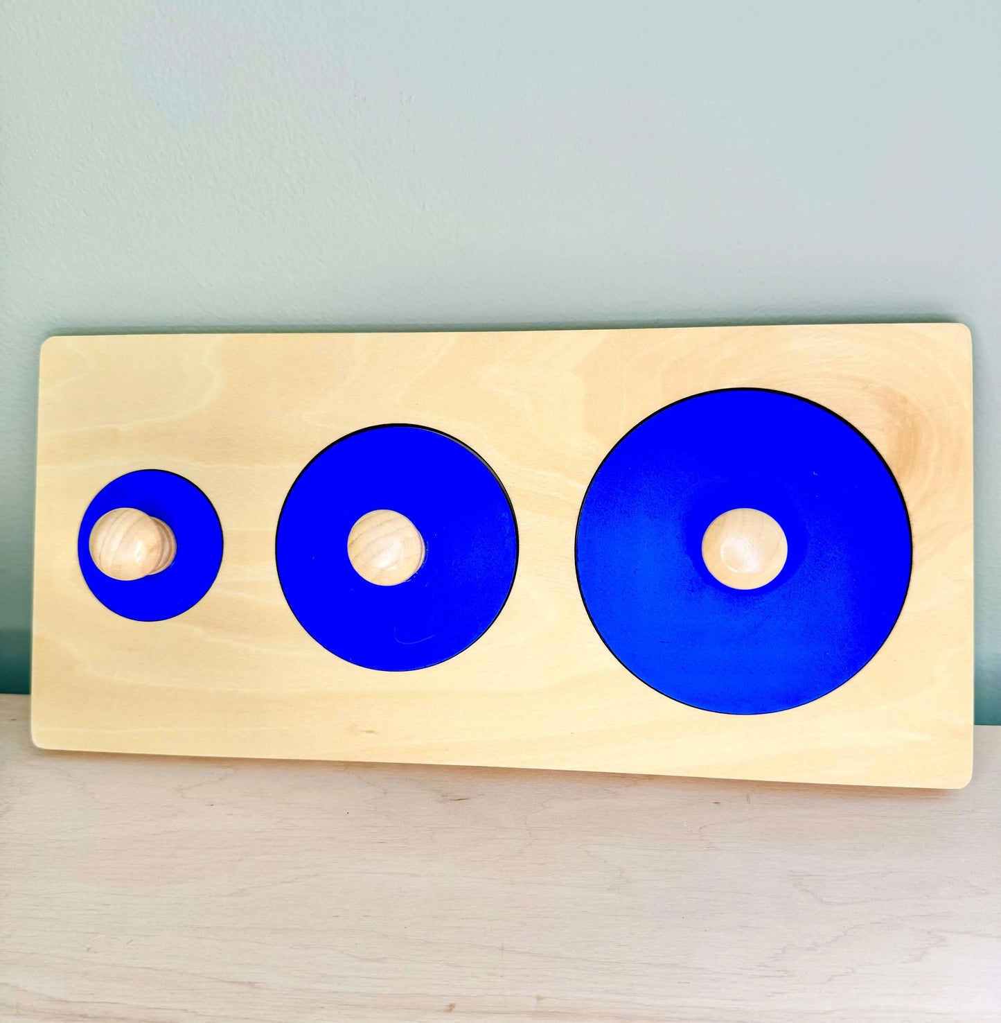 Wooden Montessori toy with three blue circles for open-ended play and spatial reasoning development. Eco-friendly educational puzzle set.