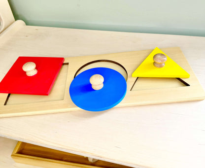 Wooden Montessori puzzle toy with red square, blue circle, and yellow triangle shapes, ideal for open-ended, eco-friendly play.