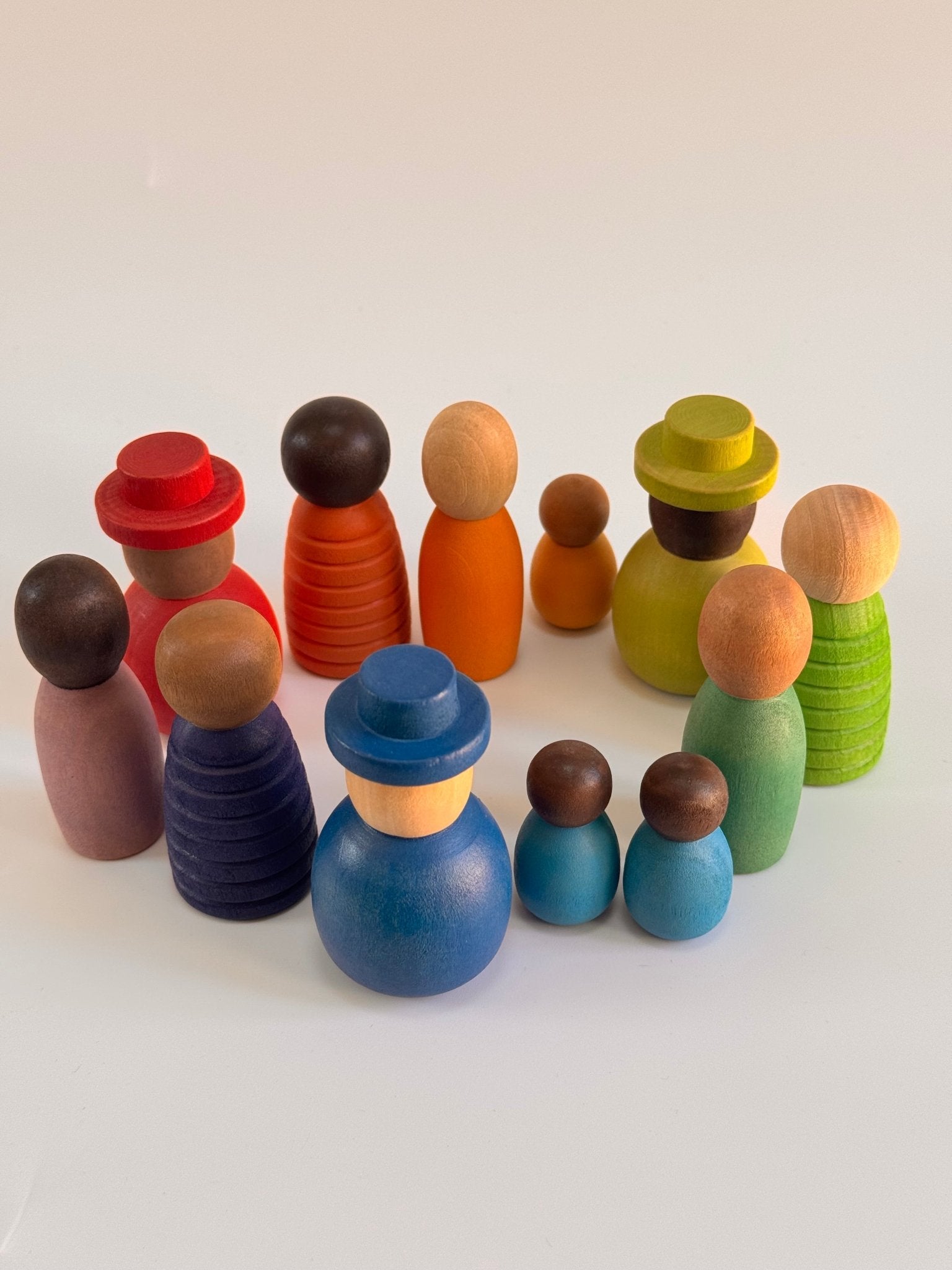 Colorful wooden peg dolls in various sizes, promoting diversity and imaginative play, featuring skin tones and vibrant colors.
