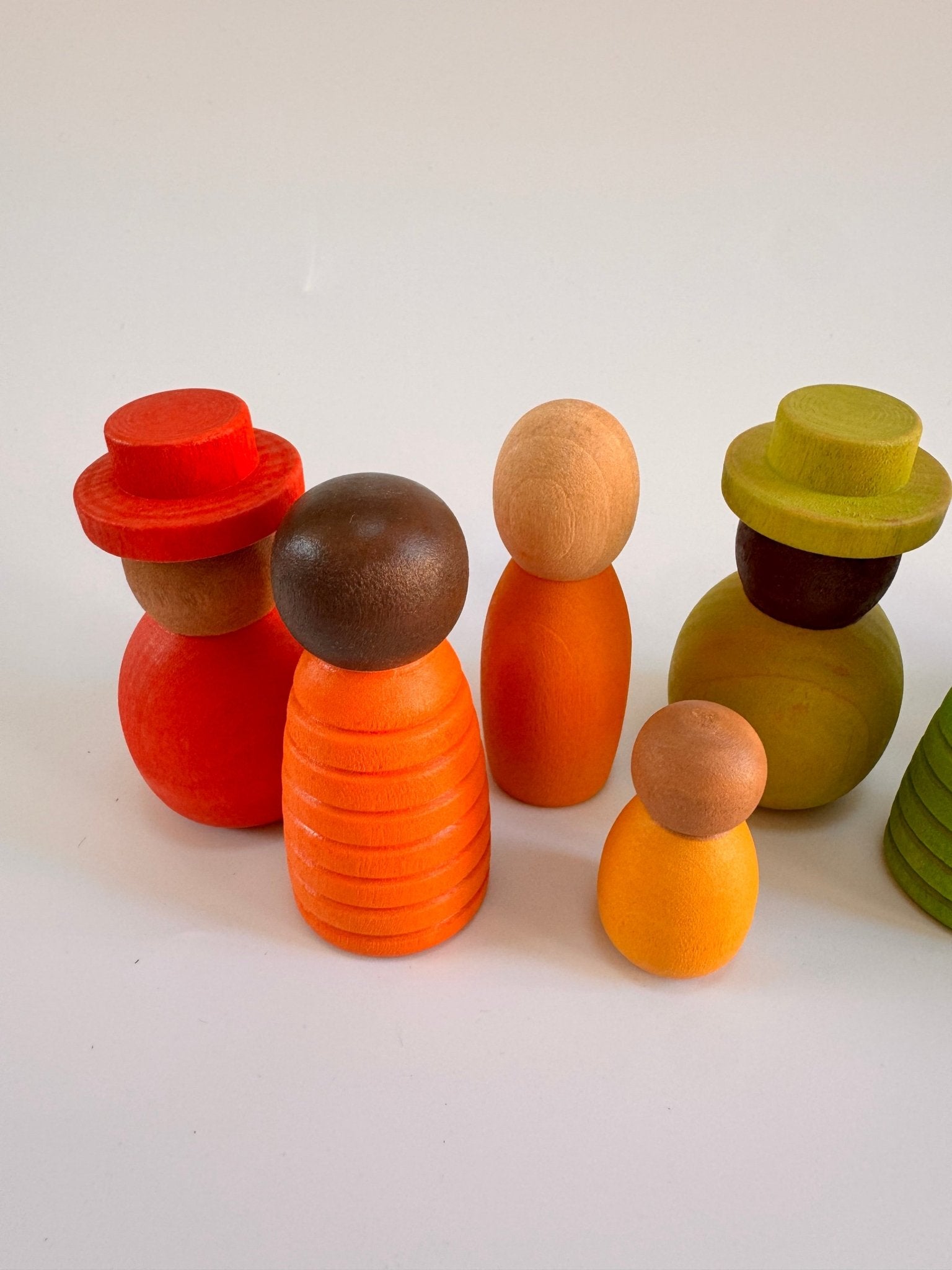 Colorful wooden peg people set in orange, green, and brown, promoting imaginative play and diversity.
