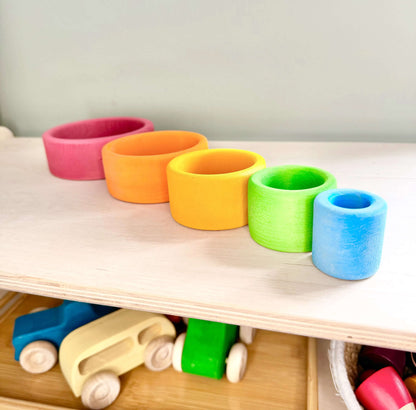 Colorful Rainbow Nesting Cups made from basswood displayed on a shelf, perfect for toddlers' open-ended play and Montessori-inspired activities.