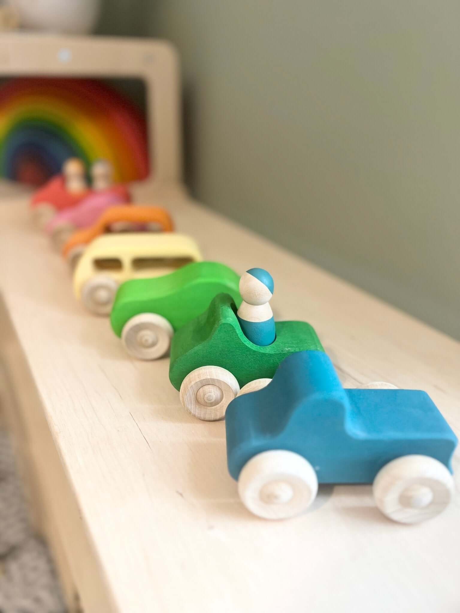 A set of colorful wooden cars and peg people, showcasing a sustainable Montessori toy made from non-toxic materials.