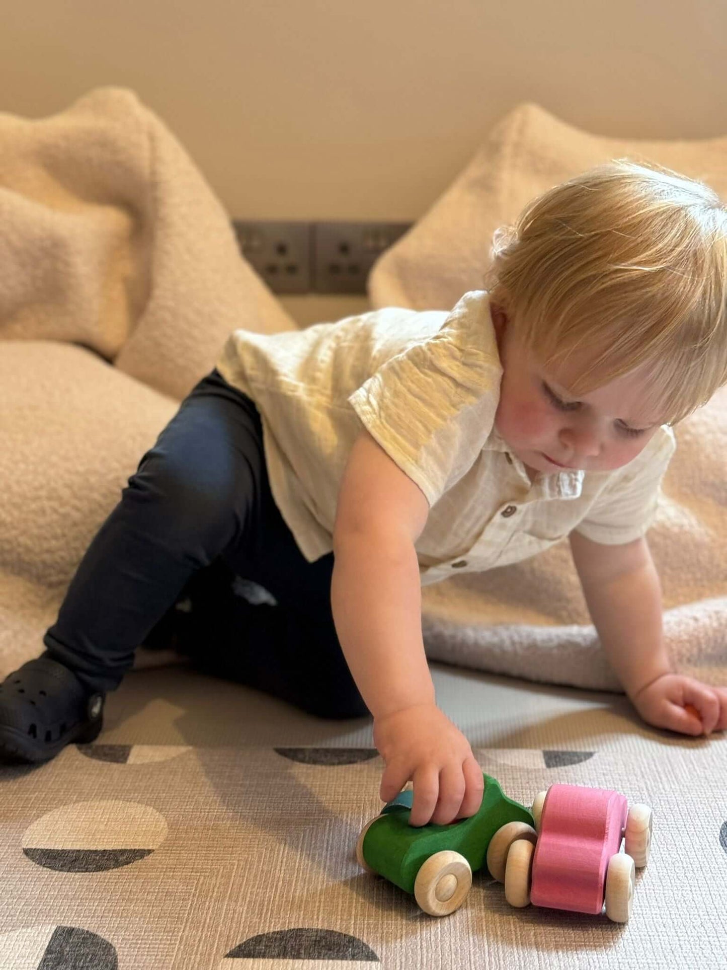 Toddler playing with Rainbow Wooden Cars, a sustainable Montessori toy set designed for education and sensory development.