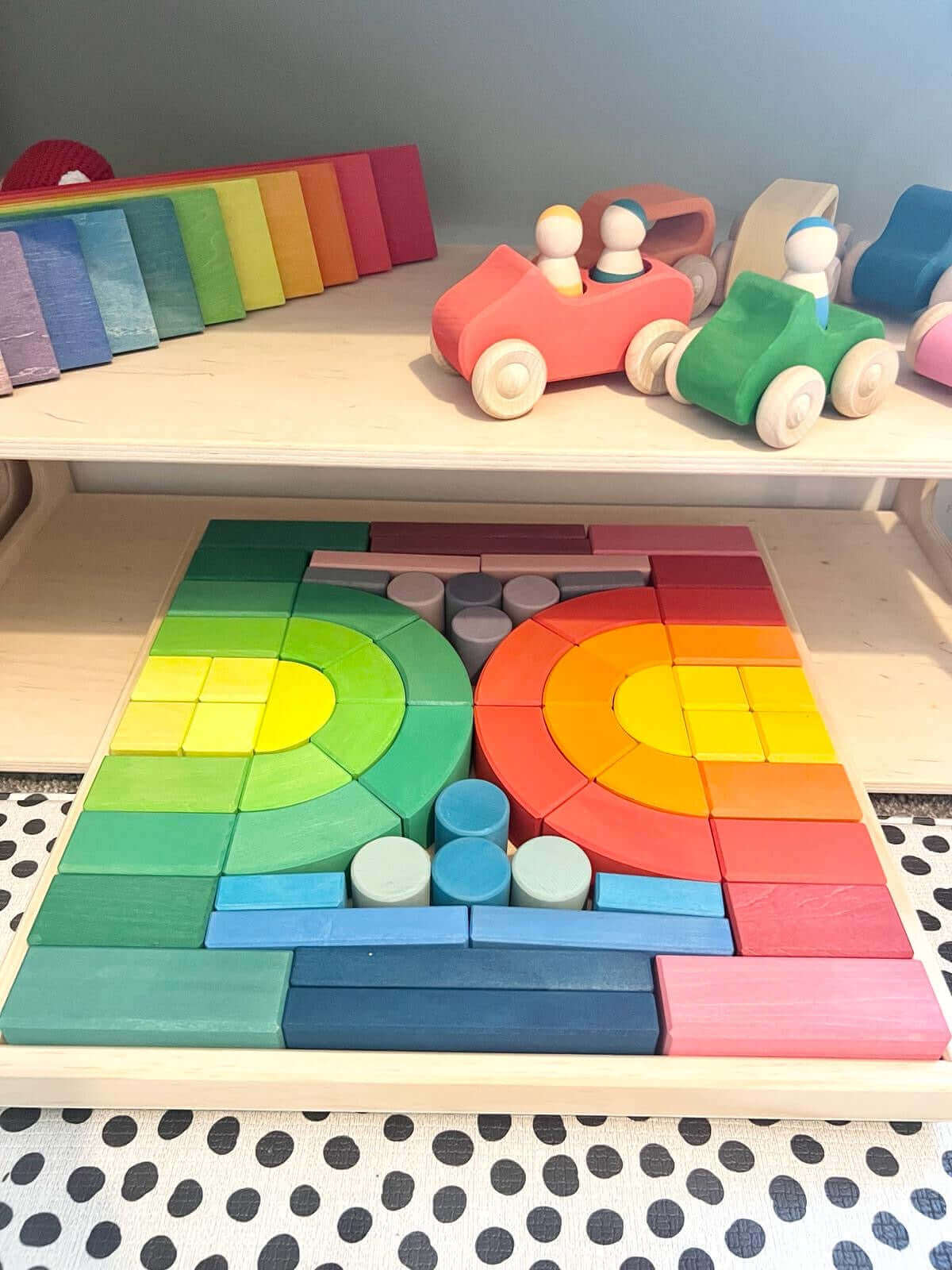 Colorful wooden Montessori building blocks and toy cars on a shelf, promoting open-ended play and creativity for children.