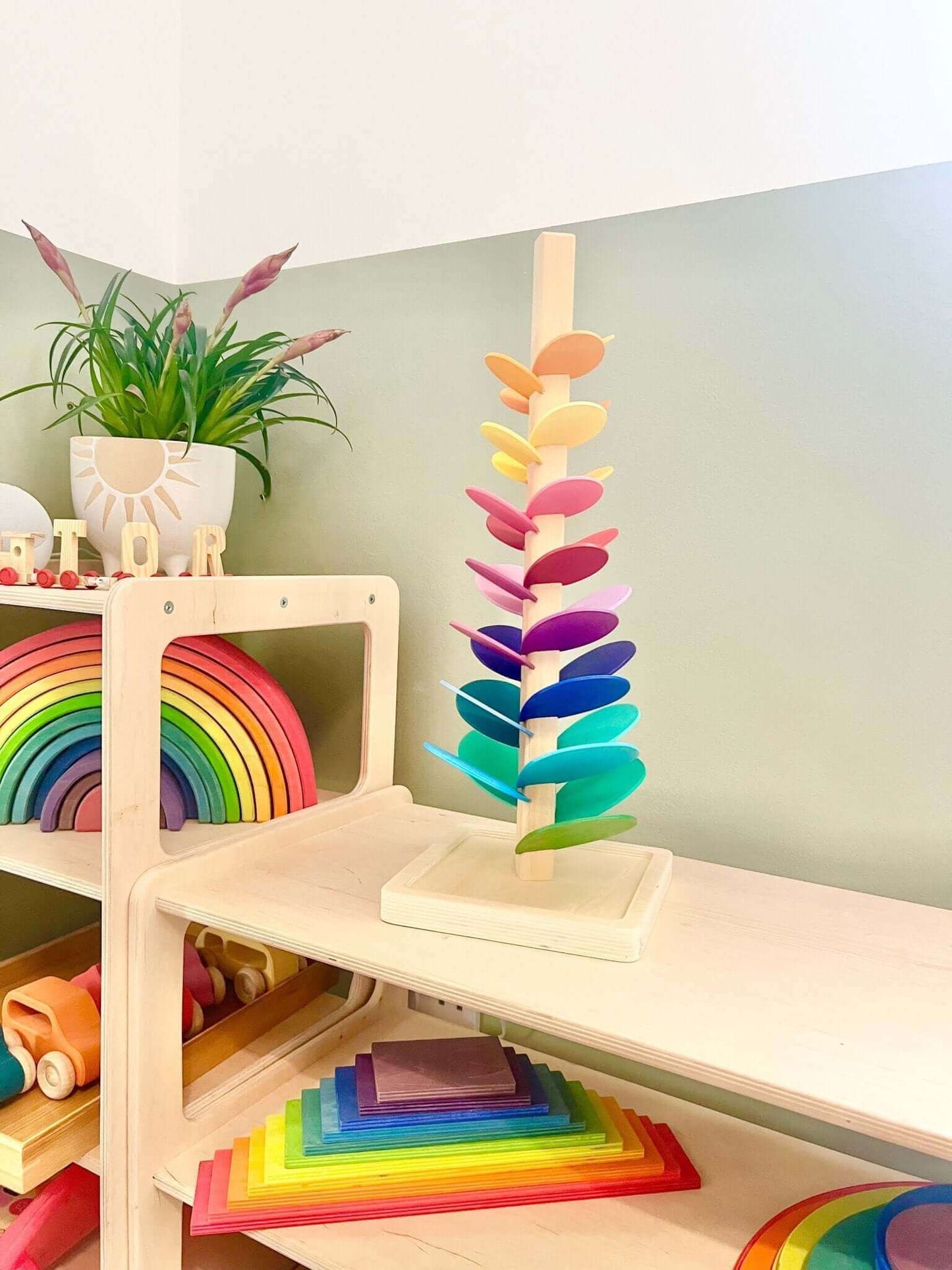 Rainbow Music Tree wooden toy for children, featuring rainbow-coloured leaves and Montessori-inspired design on a playroom shelf.