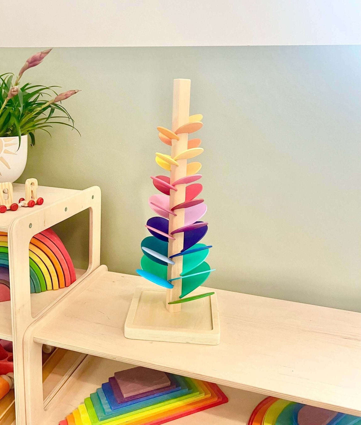 Rainbow Music Tree with colorful wooden leaves in playroom, eco-friendly Montessori-inspired open-ended play toy for children.