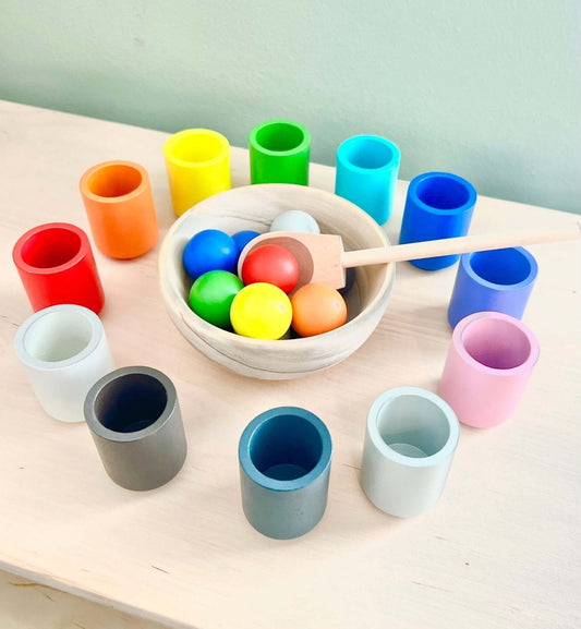 Montessori-inspired wooden toy set with brightly colored cups, matching balls, wooden bowl, and spoon for open-ended eco-friendly play.