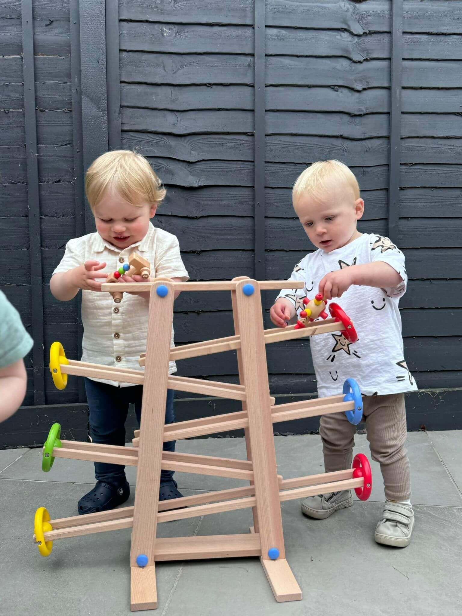 Toddlers playing with a wooden shape ramp, a Montessori-inspired, eco-friendly toy promoting open-ended play and development of problem-solving skills.