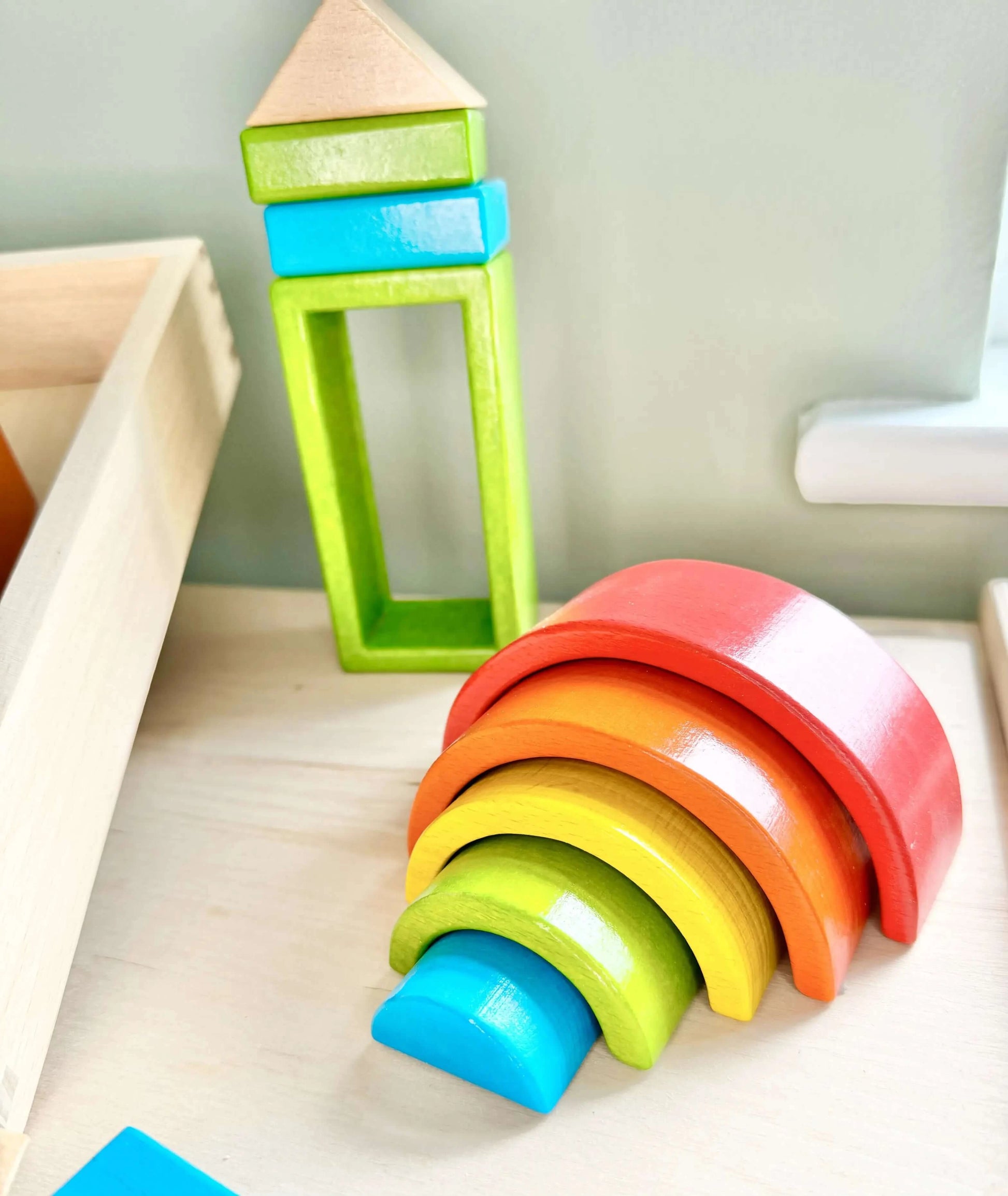 Colorful wooden hollow blocks and arches for Montessori open-ended play on a table, promoting creativity and eco-friendly fun.